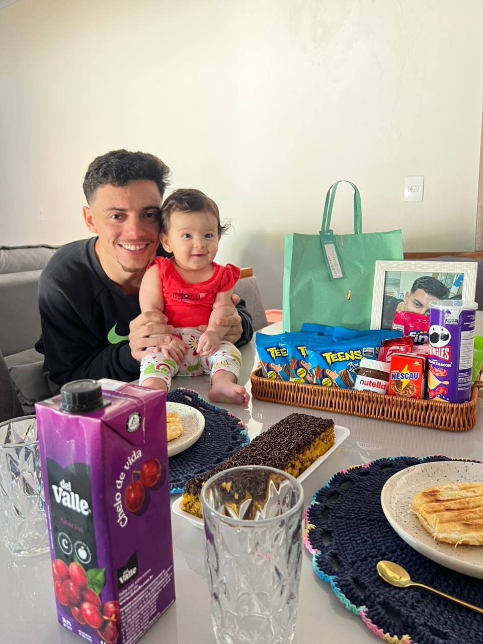Mavie em momento familiar na mesa com cesta de doces
